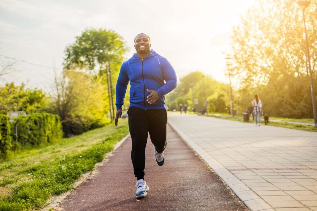 Young man jogging outside in a park.